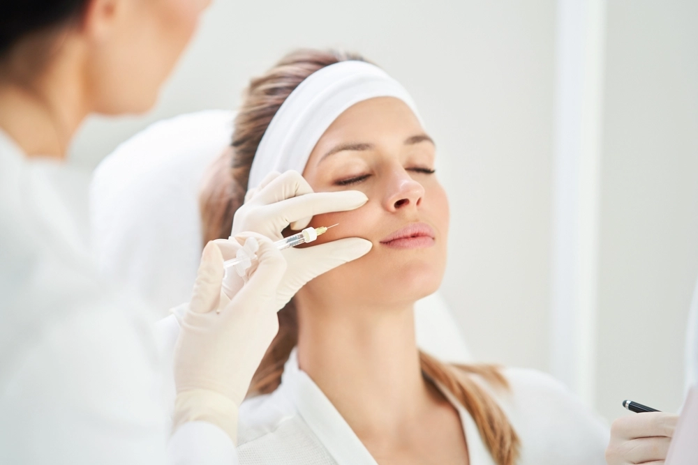 Cosmetic Professional Administering Restylane Defyne Injection To A Female Patient During Facial Enhancement Procedure