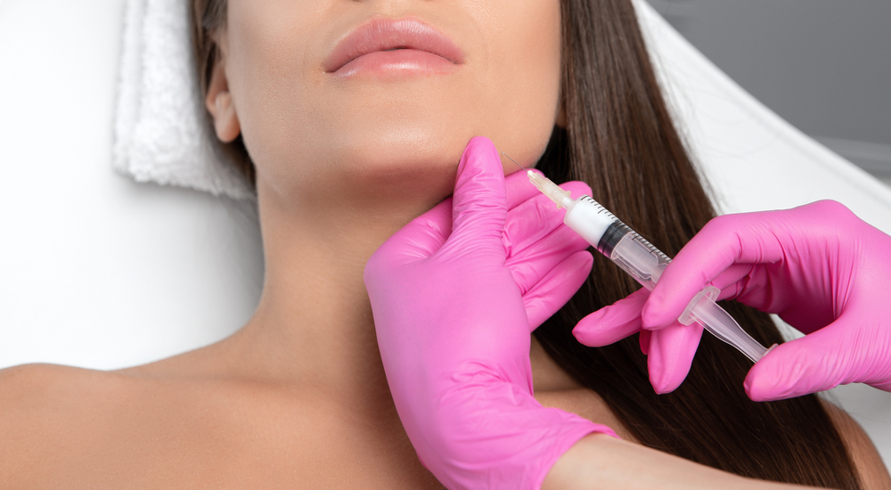 Skilled practitioner administering Botox injection to female patient for TMJ treatment, highlighting candidacy for facial cosmetic therapy