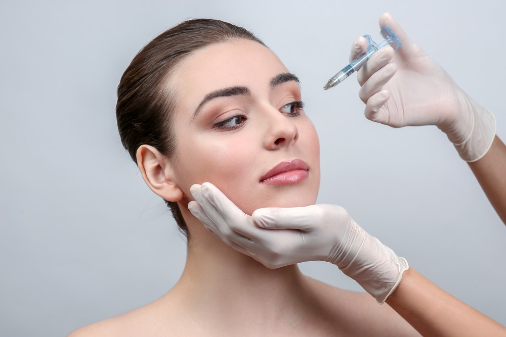 Cosmetic Expert Administering Facial Filler Treatment To A Young Woman To Reduce Wrinkles And Enhance Facial Contours