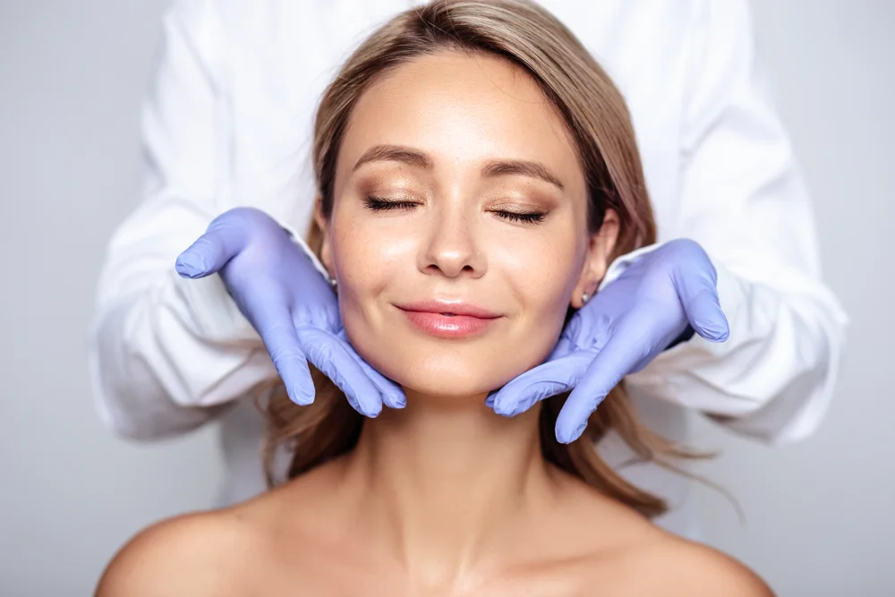 Woman Enjoying The Benefits Of A Collagen Facial Treatment With Professional Cosmetologist'S Hands Gently Framing Her Face.