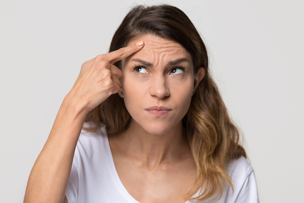 Concerned Woman Inspecting Her Forehead For Signs Of Wrinkles Due To Collagen Depletion.