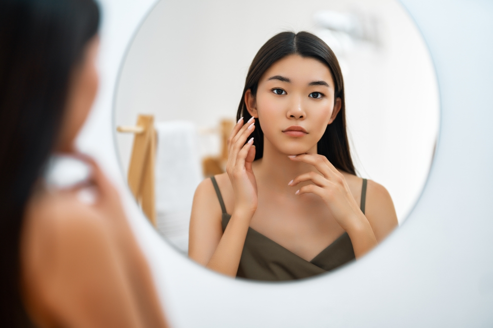Woman Touching Face While Looking At Mirror
