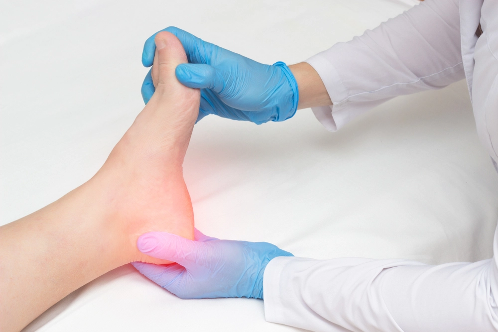 Cosmetologist inspecting patient's heel before plantar fasciitis treatment.